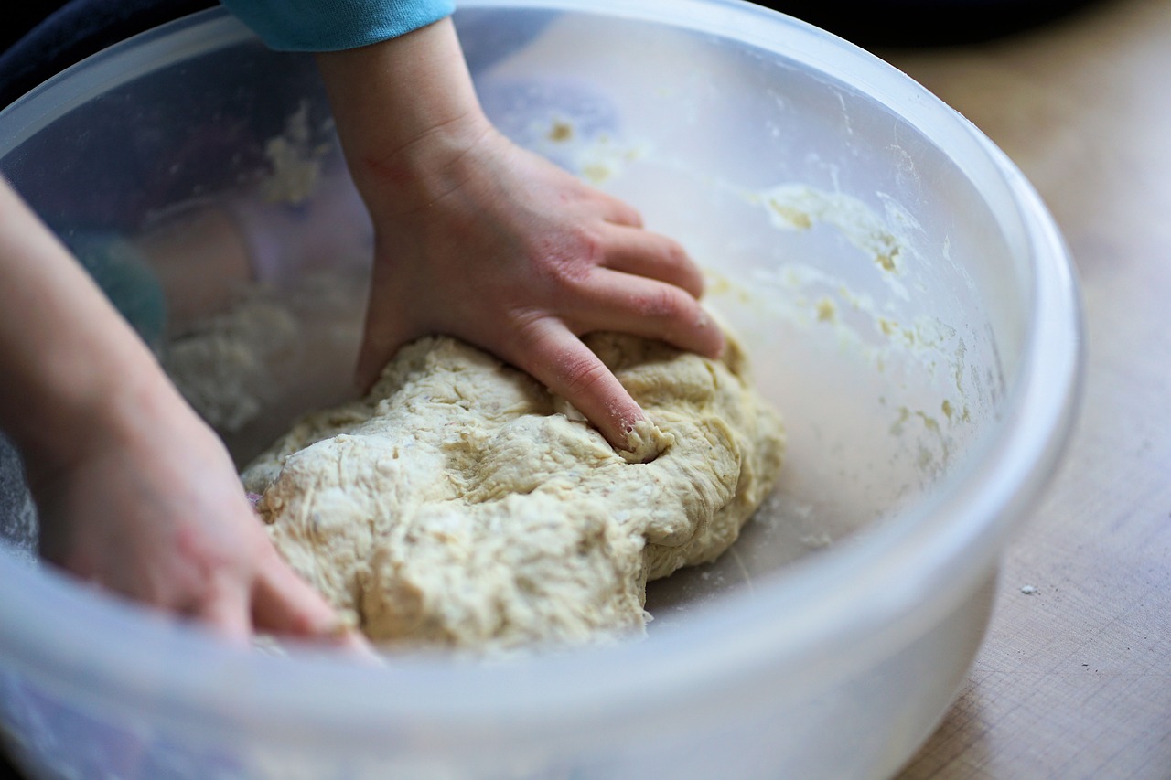 Hands kneading dough in a bowl